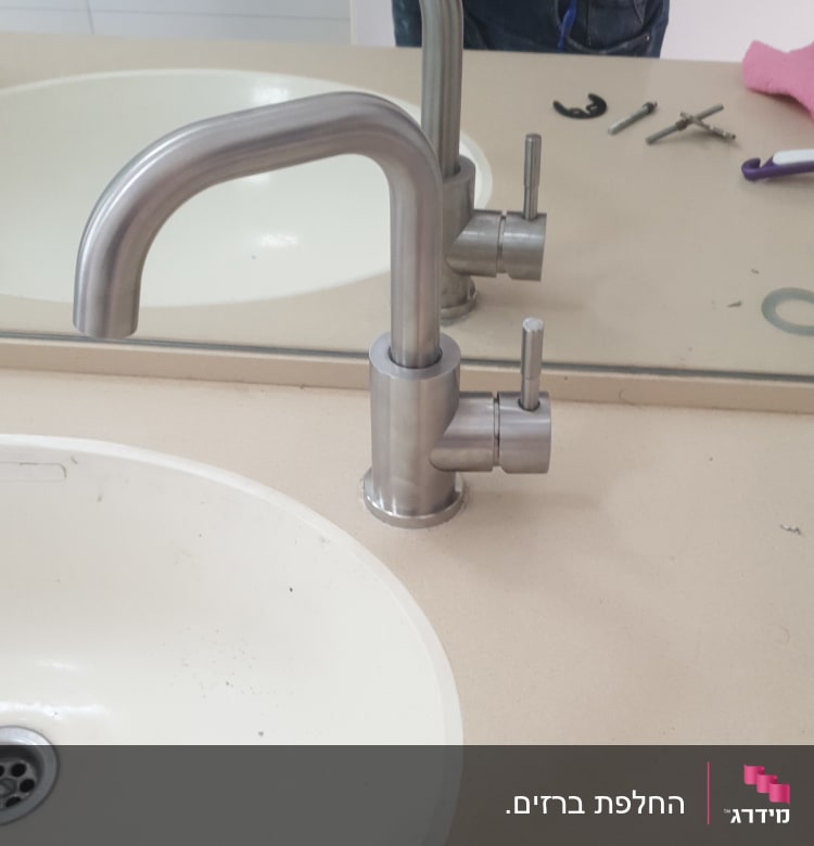 ברז נירוסטה מותקן על כיור עם כלים מסביב